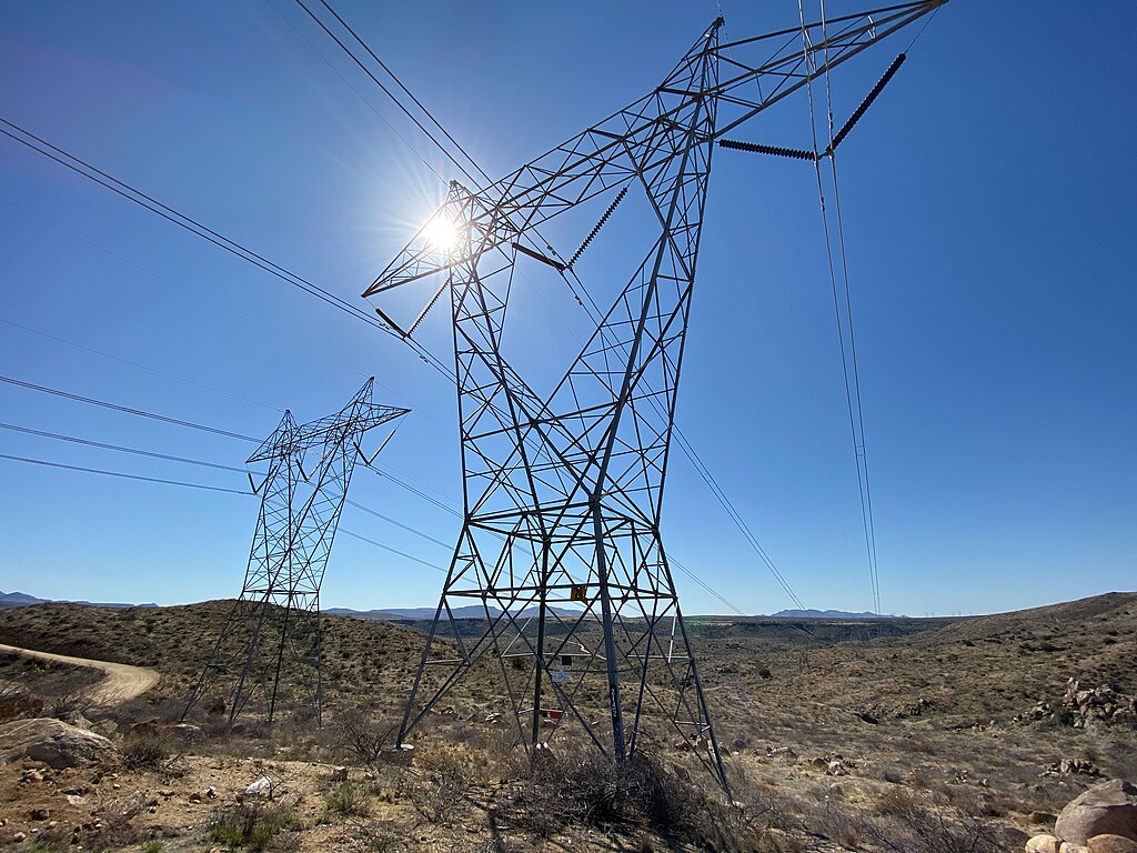 High-voltage transmission lines crossing desert terrain on public lands in Arizona.
